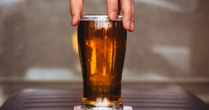 person grabbing a glass filled with beer