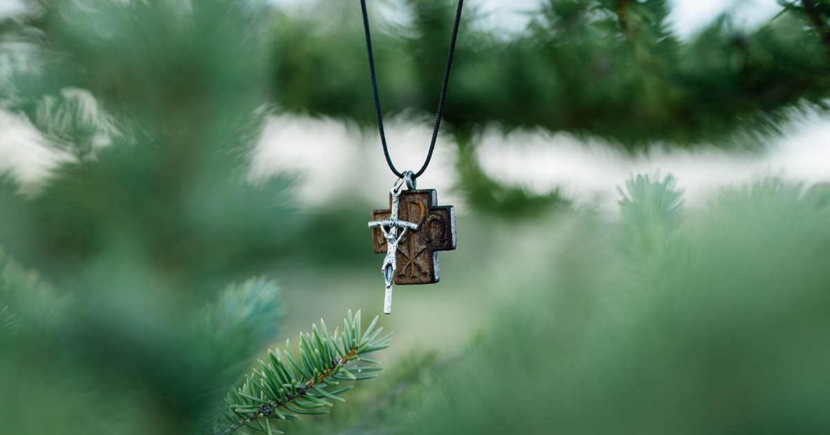 cross necklace hangs on tree branch