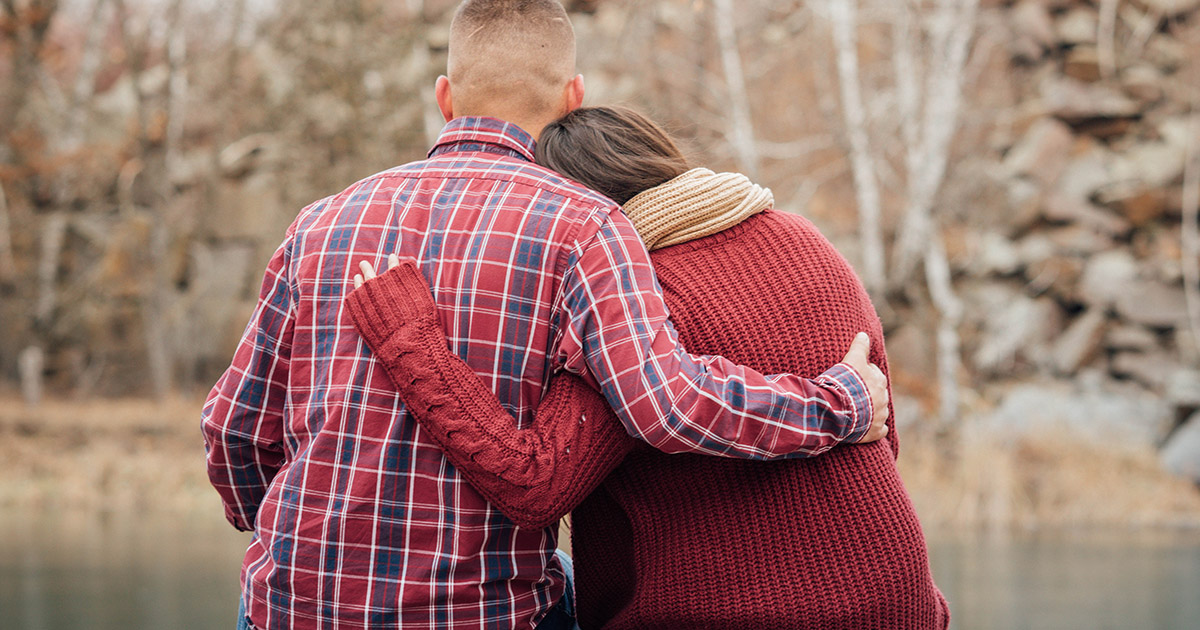 two people comfort each other while sitting outside